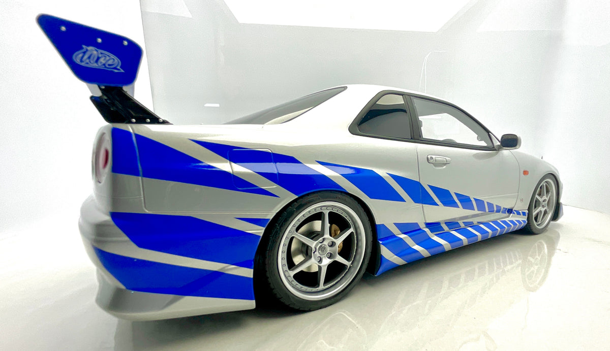 Vista laterale posteriore della Nissan Skyline R34 di Fast & Furious, con livrea blu e alettone.