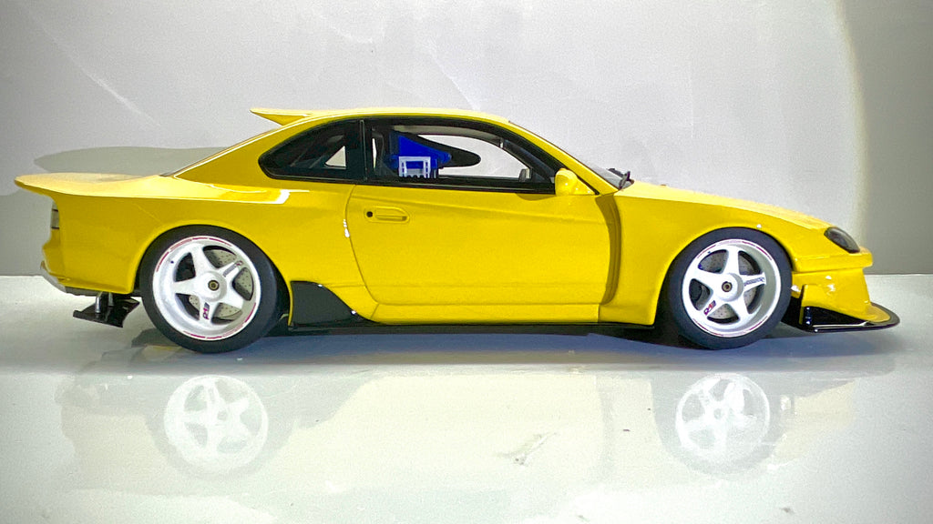 Vista laterale del modellino Kyosho Nissan Silvia S15 gialla con cerchi bianchi.
