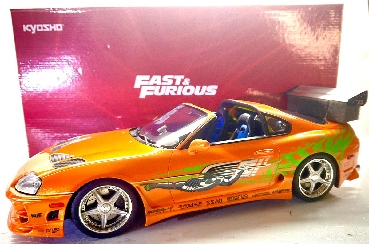Foto con scatola rossa: Toyota Supra Fast & Furious arancione Kyosho in resina scala 1:12, vista a tre quarti con confezione originale sullo sfondo