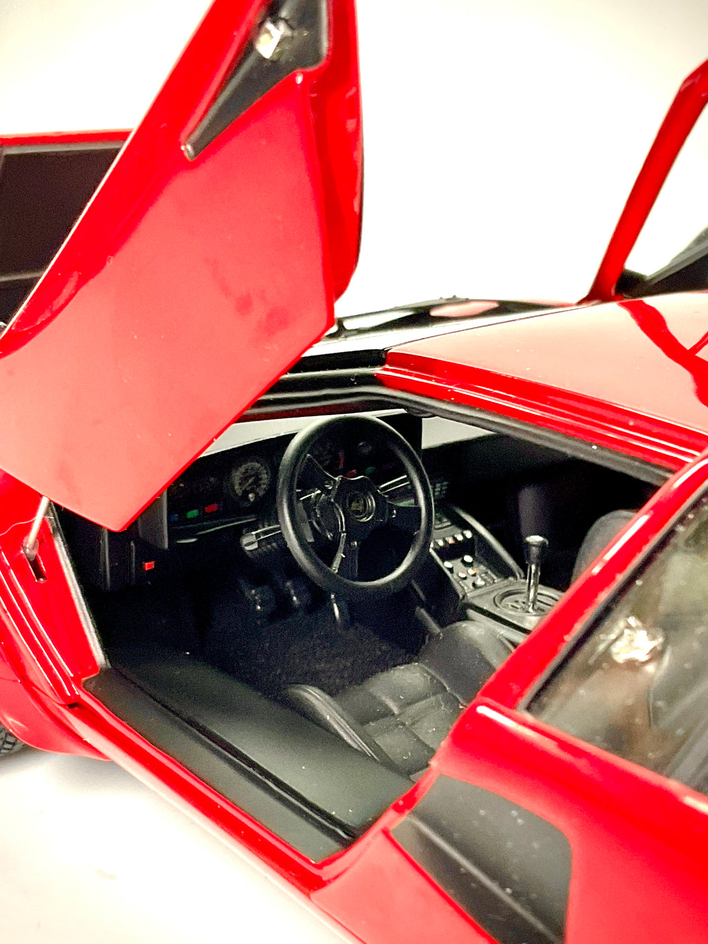 Interni della Lamborghini Countach Kyosho 08320RBKG, con sedile nero, volante, cruscotto e cambio a griglia.