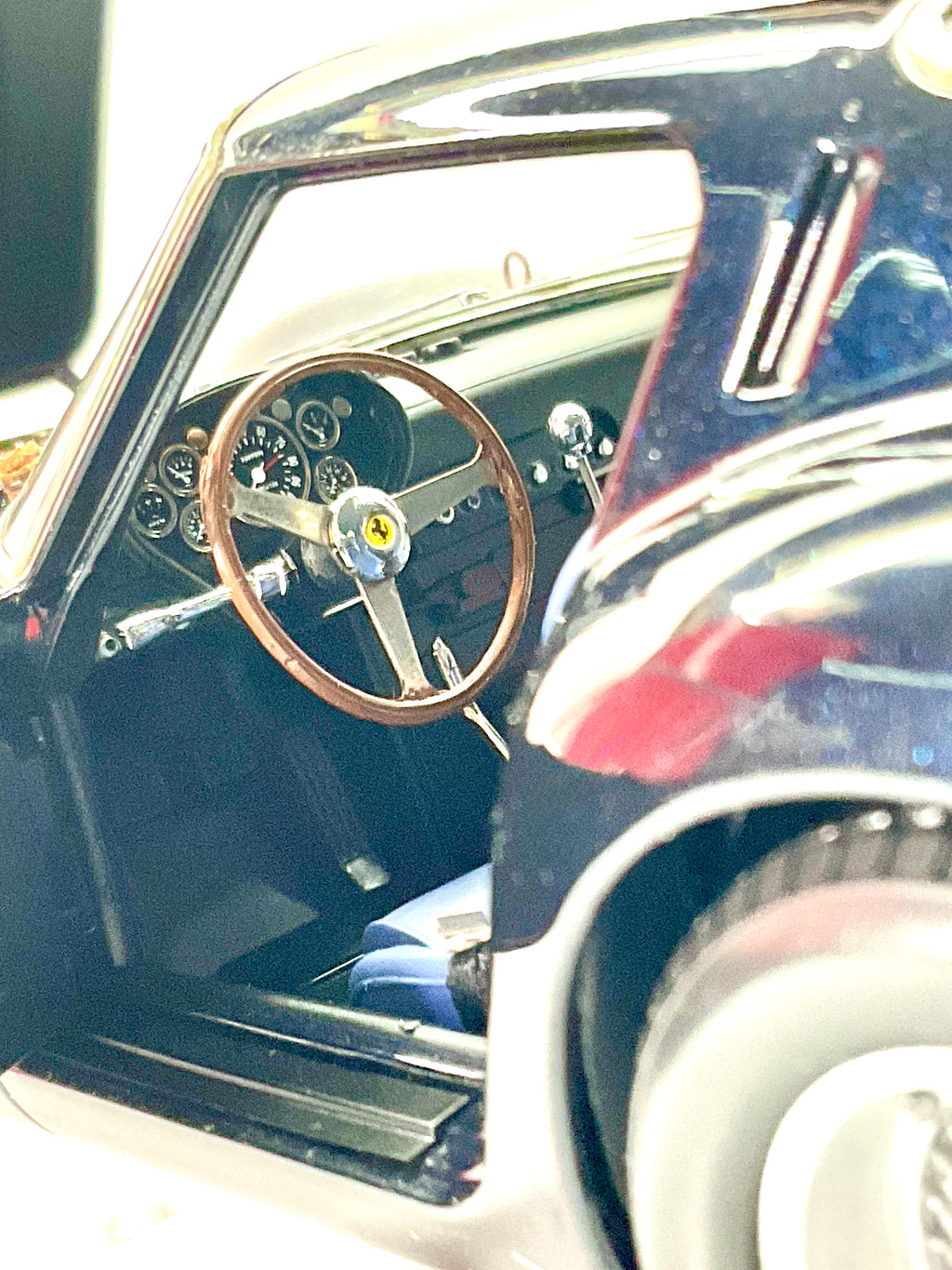 Interni della Ferrari 250 GTO Kyosho, con volante a tre razze, strumenti del cruscotto e sedile blu.